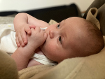 Das Bild zeigt ein Baby, das auf einer Decke liegt.