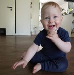 Ein Baby (Junge) sitzt am Boden und lacht, er trägt ein blaues Shirt und eine blaue Hose. Ein Baby (Junge) sitzt am Boden und lacht, er trägt ein blaues Shirt und eine blaue Hose.
