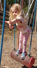 Ein ca. 5-jähriges Mädchen ist auf einem Spielplatz - es hangelt sich von einem Hindernis zum nächsten.
