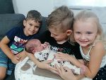 2 Jungen und 1 Mädchen halten einen Säugling im Arm.