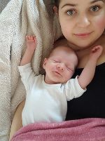 Eine Frau liegt mit einem Baby auf dem Bett. Eine Frau liegt mit einem Baby auf dem Bett.