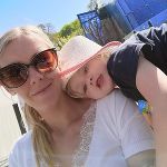 Das Bild zeigt eine Frau, auf deren Schulter ein kleines, blondes Mädchen mit Hut liegt. Das Bild zeigt eine Frau, auf deren Schulter ein kleines, blondes Mädchen mit Hut liegt.
