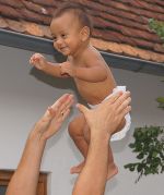Das Foto zeigt ein ca. 7 Monate altes Baby in der Luft, das aufgefangen wird. 