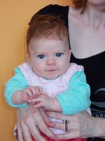 Das Bild zeigt ein vergnügtes weibliches Baby mit roten Haaren.