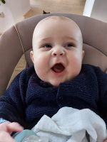 Das Bild zeigt ein Baby, das mit offenem Mund in die Kamera schaut.