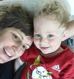 Das Foto zeigt eine Frau mit einem männlichen Baby mit blonden Haaren und blauen Augen.