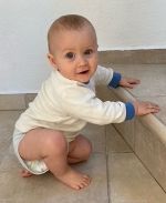Das Bild zeigt ein männliches Baby, das in die Kamera lacht.